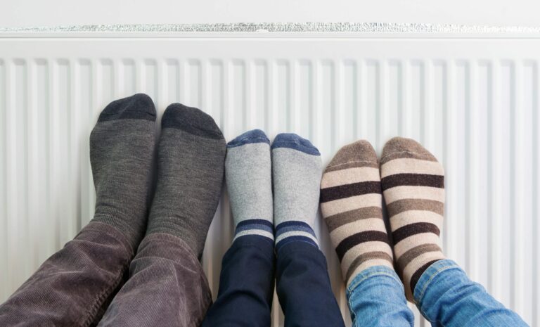 famille se réchauffant les pieds sur le chauffage