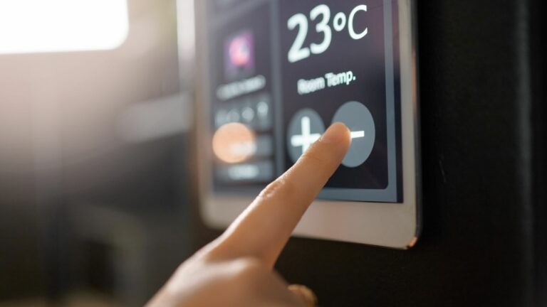 Une personne appuie sur un bouton pour régler la température de son climatiseur sur un écran tactile.