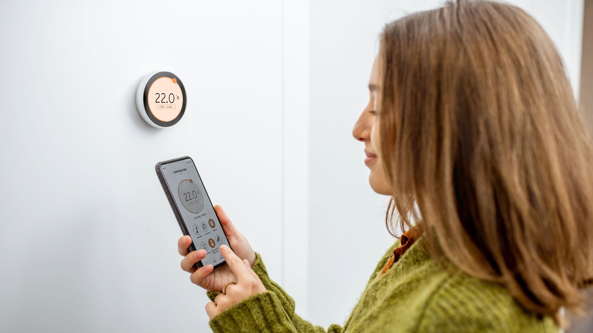 Femme réglant la température de sa chaudière gaz avec son thermostat connecté